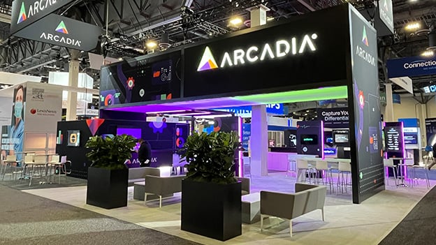 Arcadia’s custom trade show booth with dynamic purple lighting and healthcare tech graphics, designed by Catalyst Exhibits for HIMSS.