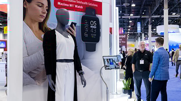 HIMSS trade show attendees explore Catalyst-built Masimo booth with health tech and data displays